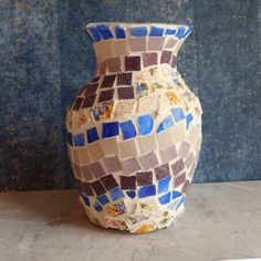 a vase that has been made out of small tiles and is sitting on a table