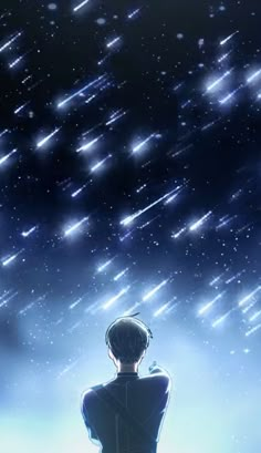 a man sitting on top of a bench under a sky filled with stars