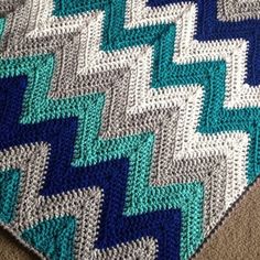 a crocheted blanket is laying on the floor with it's diagonal design