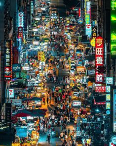 an aerial view of a busy city street at night with lots of neon signs on the buildings