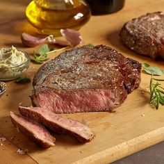 some meat is sitting on a cutting board next to other food and condiments