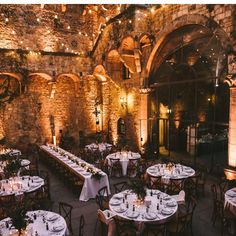 tables and chairs are set up in the middle of an old building with lights strung from it