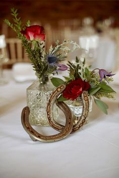 a vase with flowers in it sitting on a table next to some wine glasses and napkins