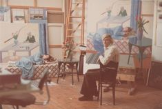 a woman sitting at a table in front of paintings