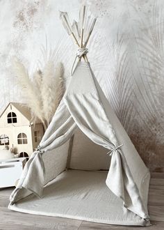 a teepee tent sitting on top of a wooden floor next to a doll house