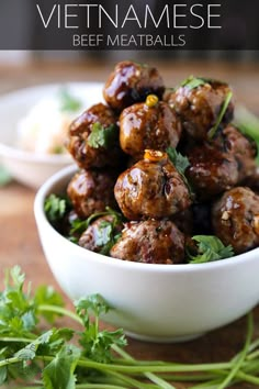 a white bowl filled with meatballs and garnished with cilantro leaves