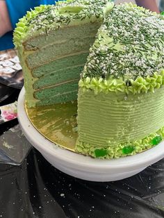 a green cake sitting on top of a white plate next to a slice taken out of it