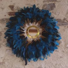 a blue and brown feather decoration with a mirror in the middle on a stone floor