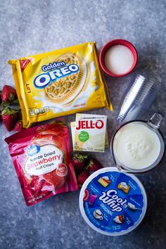 ingredients to make strawberry shortcakes laid out on a counter top, including milk, yogurt, and strawberries