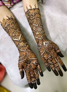 two hands with henna tattoos on them, one is showing off the intricate design