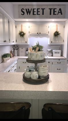 a kitchen with white cabinets and an island in front of the counter top that has coffee mugs on it