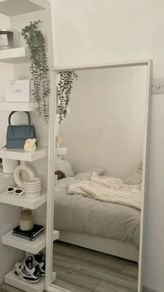 a bedroom with a bed, mirror and shelves on the wall next to each other