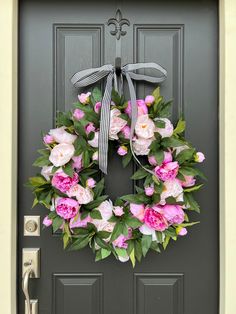 a wreath with pink and white flowers is hanging on the front door