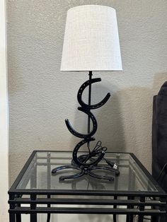 a table with a lamp on top of it next to a black couch and chair