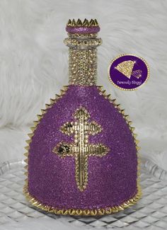 a purple glass bottle with a cross on the front and gold trimmings around it