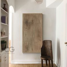 a chair sitting in front of a painting on the wall next to a book shelf