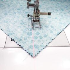 the sewing machine is stitching fabric with pink thread on blue and white patterned background