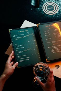 a person holding a drink in front of two menus