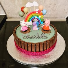 a birthday cake with peppa pig and rainbow decorations