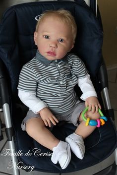 a baby sitting in a stroller holding a toy