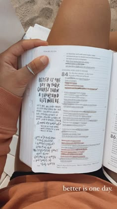 a person is reading a book with writing on the pages and holding it in their hands