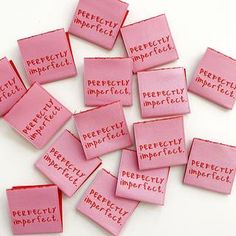 pink pieces of cloth with words written on them that spell perfectly imperfectecity and are arranged in the shape of rectangles