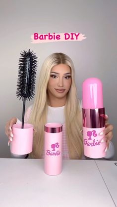 a woman with blonde hair holding two pink cups and a brush