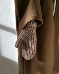 a brown coat with a knitted mitten hanging from it's back pocket