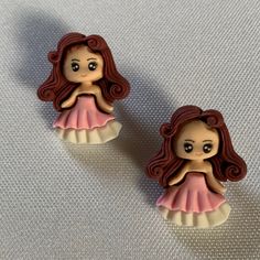 two little dolls sitting on top of a white cloth covered table next to each other