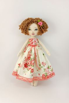 a doll with brown hair wearing a white dress and pink flowers on it's head