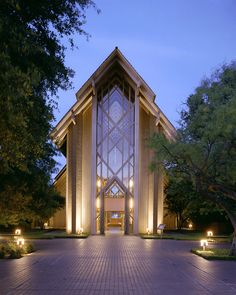 the entrance to a building lit up at night with lights shining on it's sides