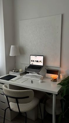 a laptop computer sitting on top of a white desk next to a lamp and chair