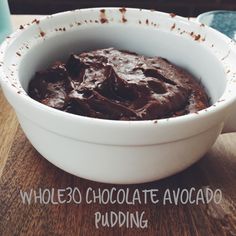 a white bowl filled with chocolate pudding on top of a wooden table