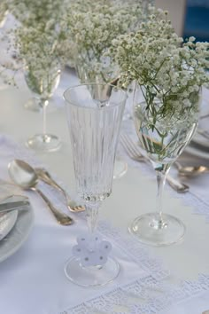 the table is set with silverware and glass vases filled with baby's breath