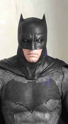 a man in a batman costume standing next to a white wall