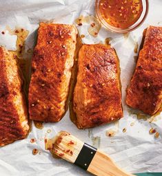 four pieces of fish sitting on top of wax paper next to a brush