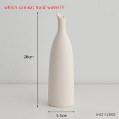 a white vase sitting on top of a table next to a measuring line with the measurements