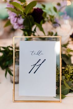 the table numbers are displayed in a gold frame on top of a white table cloth