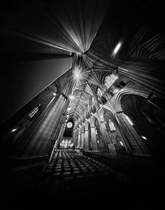 the interior of a cathedral lit up at night with beams of light coming from the ceiling