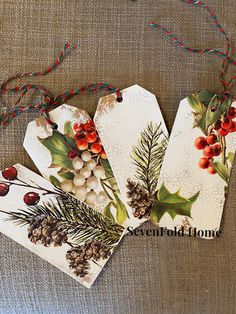 four tags decorated with holly berries and pine cones