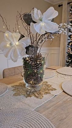 a vase filled with white flowers sitting on top of a wooden table next to a christmas tree