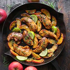 chicken and apples in a skillet with limes, lemon wedges and rosemary