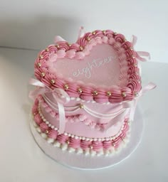 a pink heart shaped cake sitting on top of a table