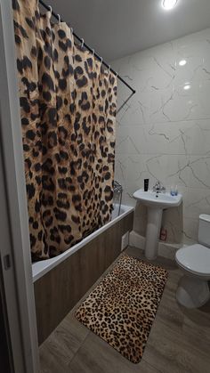 a bathroom with a leopard print shower curtain next to a white toilet and bathtub