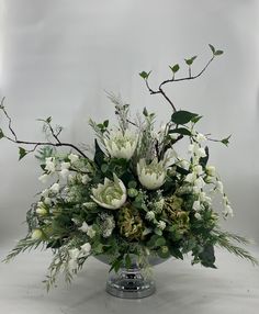 a vase filled with white flowers and greenery