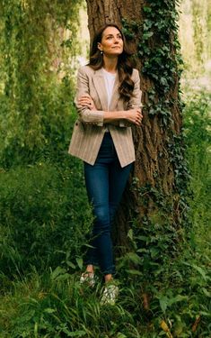 a woman leaning against a tree in the woods