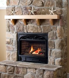 a fire place in a living room with rocks on the wall and wood flooring