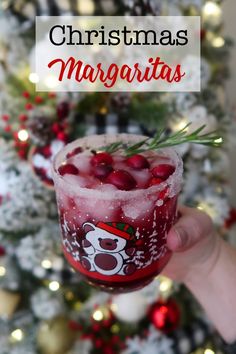 someone holding up a drink in front of a christmas tree with the words, christmas margaritas