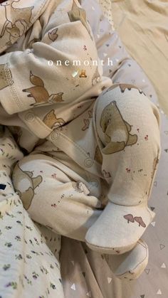 a baby laying on top of a bed wearing a bear print pajamas and headband