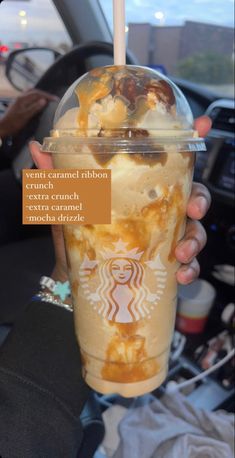 a person holding up a starbucks drink with caramel and ice cream on the top